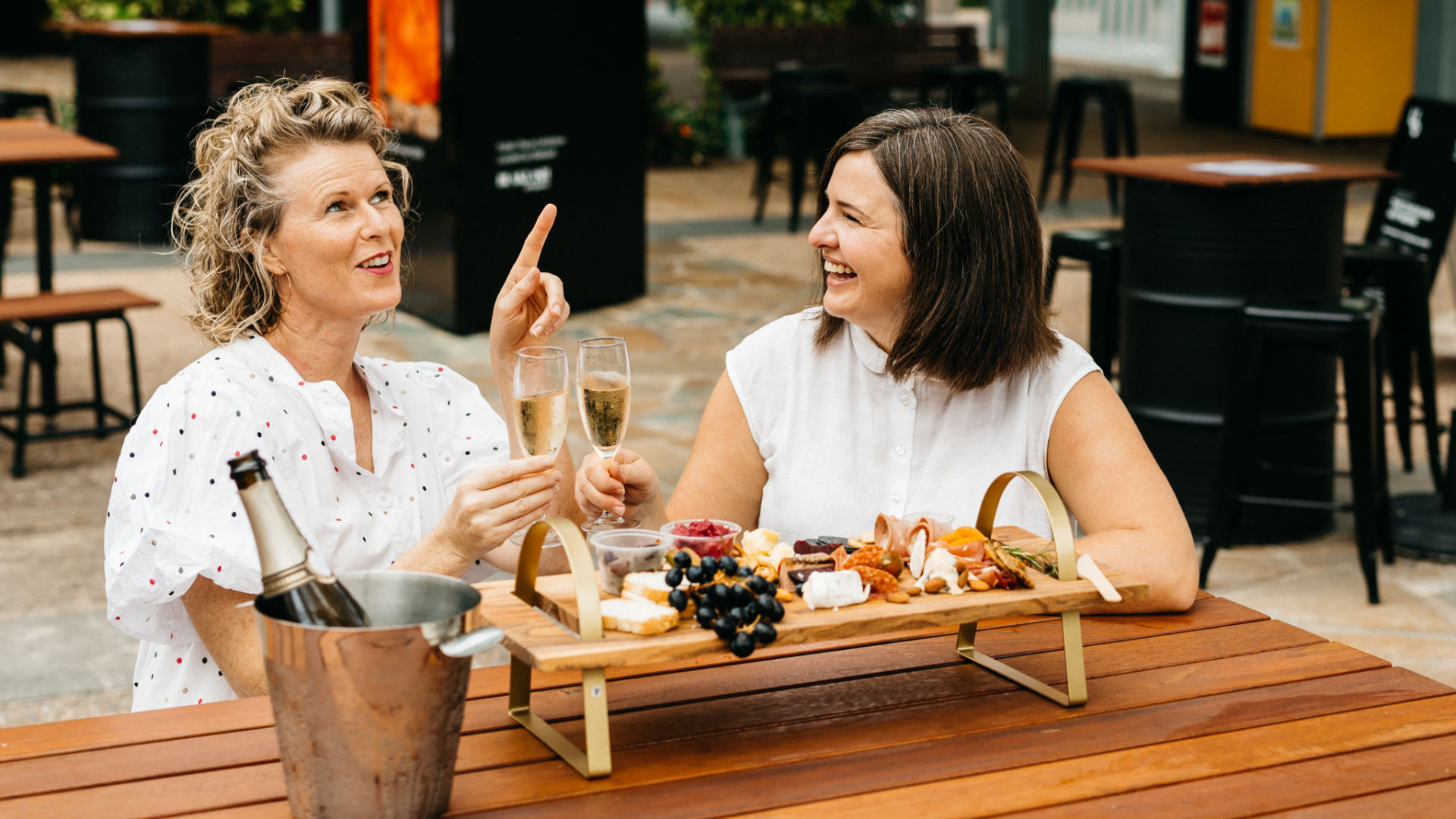 Two women sitting together sharing a cheese board
