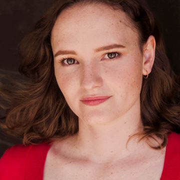 close up of woman with short auburn hair and freckles looking at camera