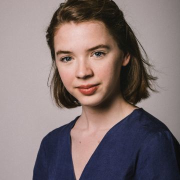 Woman with short brown hair and blue shirt looking to camera