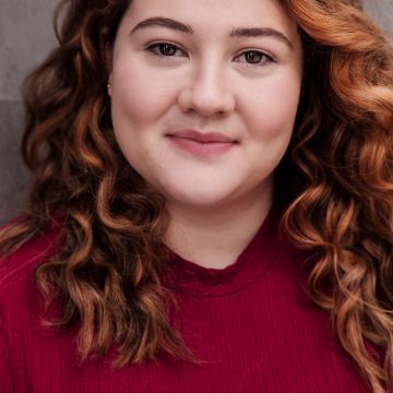 Woman with red curly hair looking at camera and smiling