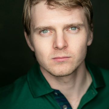 close up of man with Blonde hair and stubble looking at camera
