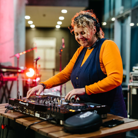 Woman smiling while pushing buttons on DJ deck