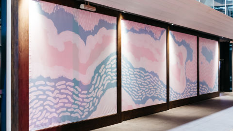Image of 4 billboards outside with continuous blue and pink abstract art covering all of them.