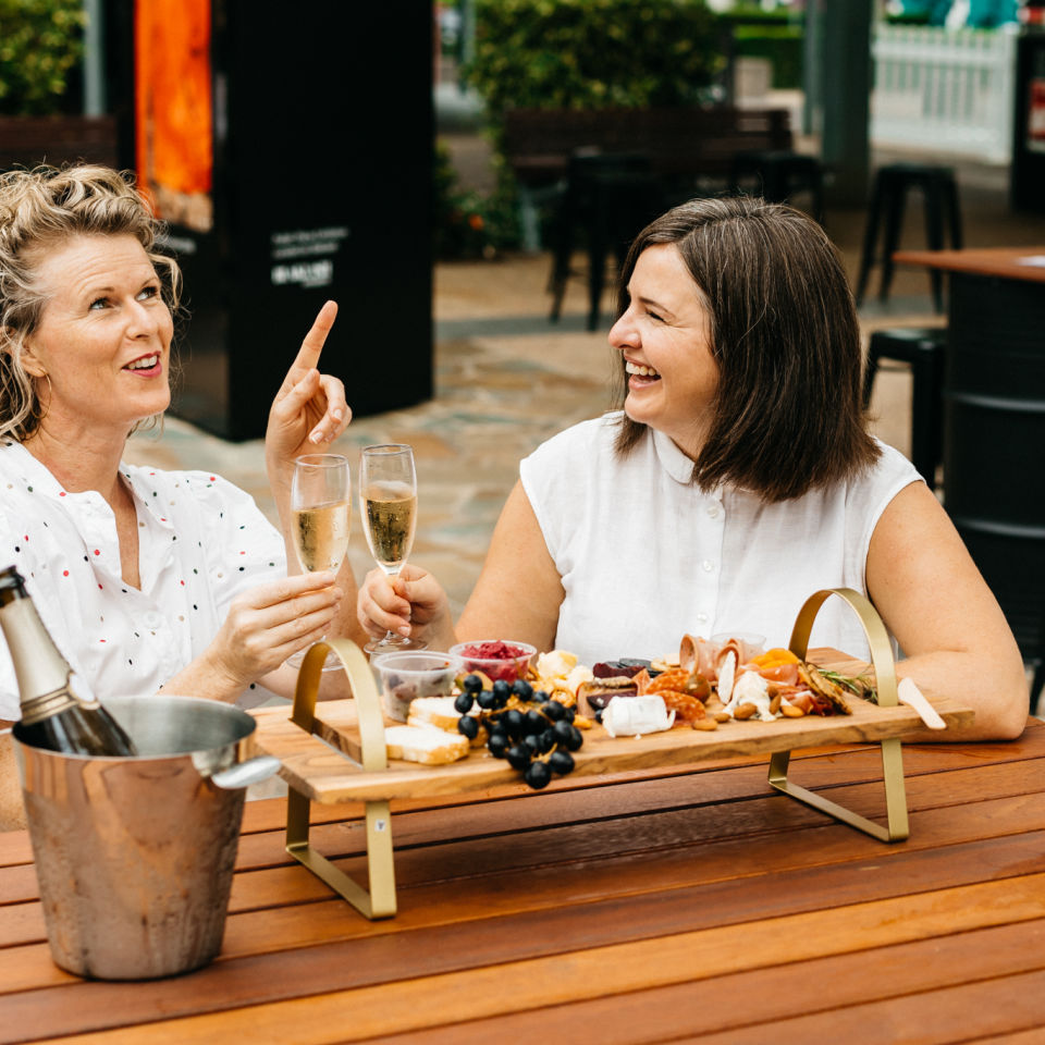 Two women sitting together sharing a cheese board